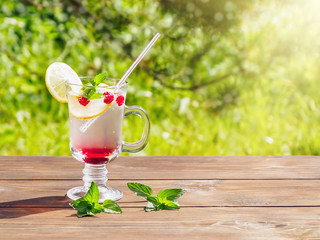 Refreshing summer cocktail with lemon, raspberry and mint a wooden table