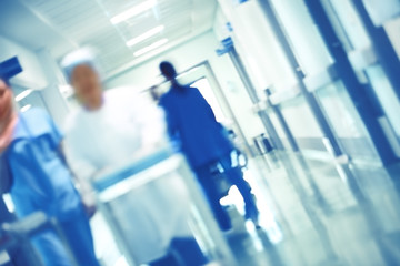 Blurred figures of walking medical staff in the hospital hallway, unfocused background