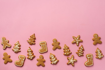 Christmas handmade cookies on pink background with copy space. Pattern of gingerbread men, snowflake, star, fir-tree, boot shapes. New year concept