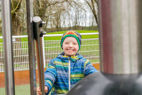 Defect,childcare,medicine and people concept- young boy with a down syndrome who is playing in a playground.