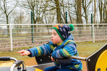 Defect,childcare,medicine and people concept- young boy with a down syndrome who is playing in a playground.