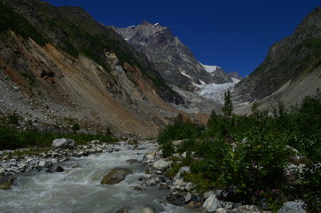 view of the glacier with river in the foreground and clear blue sky