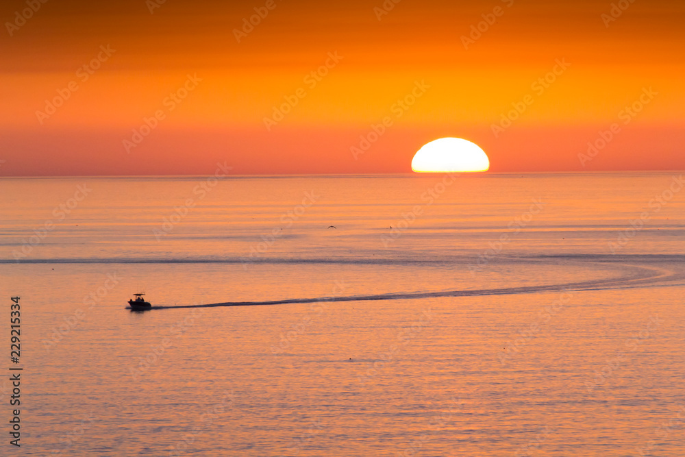 Wall mural this fishing boat heads home from fishing in front of a beautiful sunset at clearwater beach, florid