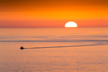 This fishing boat heads home from fishing in front of a beautiful sunset at Clearwater Beach, Florida in the Gulf of Mexico.
