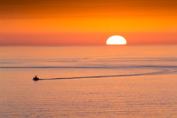 Foto auf Acrylglas Clearwater Strand, Florida Dieses Fischerboot fährt nach Hause vom Angeln vor einem wunderschönen Sonnenuntergang am Clearwater Beach, Florida im Golf von Mexiko.