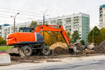 Road repair on a city street, an excavator bucket rakes in the ground