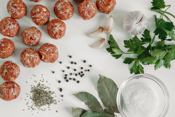 Raw meatballs, Bay leaf, pepper, garlic and herbs on the table. Top view