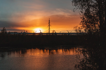 Fototapeta na wymiar Highway and power lines on sunset background, view from the riverbank
