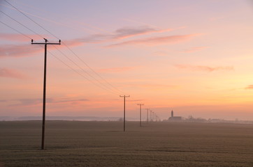 Fototapeta na wymiar Morgenstimmung mit Strommasten und Kirche