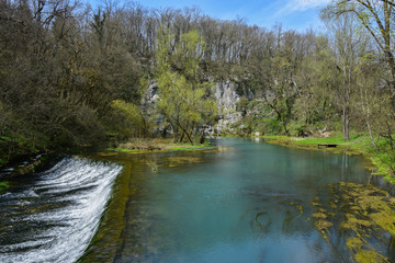 Fototapeta na wymiar Krupa Spring (Izvir Krupa) in Bela Krajina, southern Slovenia, is a big karst spring below rock wall. It is protected as natural heritage and special habitat of water spices.