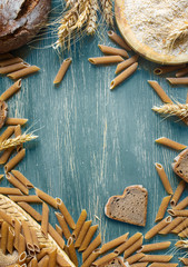 Wholemeal pasta and bread on rustic background