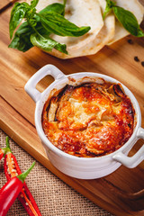 Celery root gratin with cheese and mushrooms on wooden board. Close up
