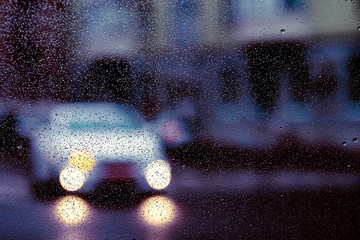 City road seen through rain drops on the car windshield