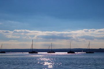 Fototapeta na wymiar A nice view on a calm lake with the silhouettes of a few sailboats