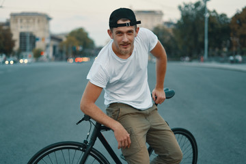 A Young, handsome man posing while sitting on bike, on city road