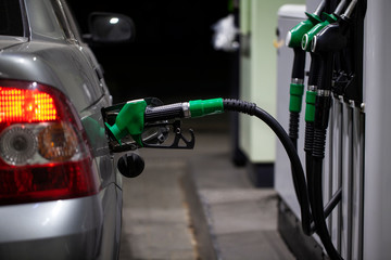 Fuelling gun inserted into the tank of gray car