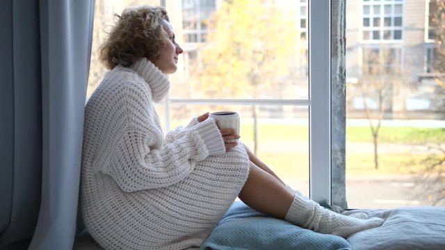 Lonely Woman Sitting By The Window With Cup