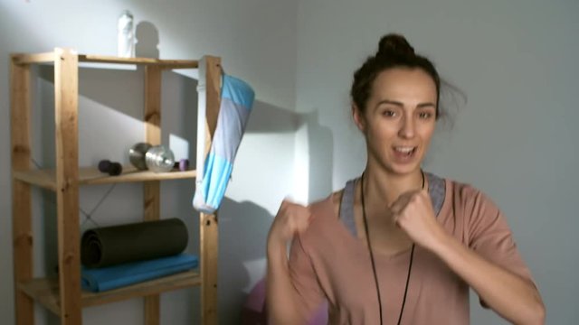 Medium shot of female fitness trainer showing talking and showing squat and punch exercise before camera
