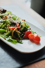 plate with pieces of fried fish and salad on wooden table side view