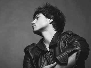 Portrait of Handsome Young Man. A Men in a Leather Jacket posing on a Gray Background. Black And White Photo