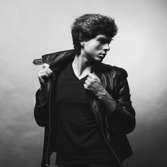 Portrait of Handsome Young Man. A Men in a Leather Jacket posing on a Gray Background. Black And White Photo