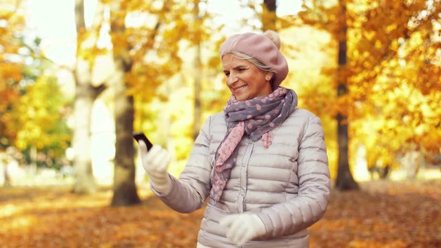 old age, retirement and technology concept - happy senior woman taking selfie by smartphone at autumn park
