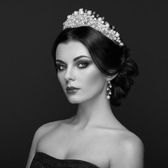 Fashion Portrait of Beautiful Woman with Tiara on head. Elegant Hairstyle. Perfect Make-Up and Jewelry. Black and White Photo
