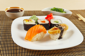 Sushi set, hiyashi wakame salad and soy sauce on a bamboo mat close up.