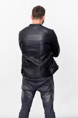 Rear view of young man in black jacket and jeans against white background