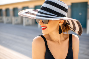 Close-up portrait of a beautiful woman in striped hat on the beach near the old locker rooms in Deauville, famous french resort in Normandy - obrazy, fototapety, plakaty