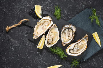 Opened Oysters with lemon on dark stone background