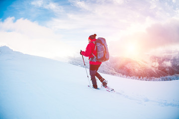 A man in snowshoes in the mountains.
