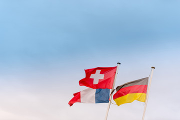 flags of Germany, Switzerland and France waving in the wind