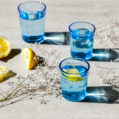 Water with a lemon in a Color Glass. Concept of Energy and Purity. On the Gray Stone Background.Bright Hard Sunlight Deep Shadow.selective focus. Detox.healthy eating