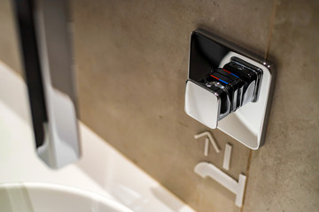 Chrome button to start tap water in public toilet