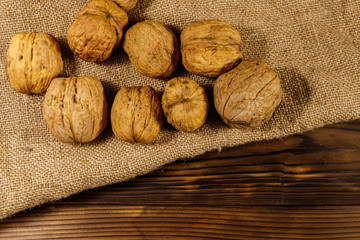 Walnuts on burlap on wooden table. Top view