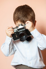 Little boy with aged retro camera. Child with an old camera