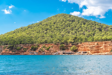 Fototapeta na wymiar Ibiza, Sa Caleta beach, old fisherman’s sheds on the shore, beautiful red cliffs 
