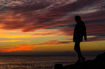Fototapeta premium The silhouette of girl that standing on the stone near the sea