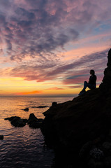 The silhouette of girl that standing on the stone near the sea