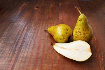 Ripe conference pears on wooden table, one cut in half