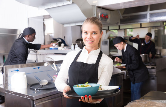 Waitress in restaurant kitchen with ordered meals