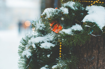 winter holidays and decoration concept - red christmas ball on fir tree branch covered with snow