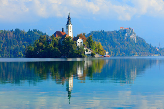 Bled lake island, St Martin Catholic church and Castle with mountain Range, Slovenia, Europe. Landscape in Slovenia, nature in Europe.  Foggy Triglav Alps with forest, travel in Slovenia.