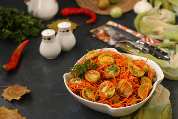 Korean-style salad with green tomatoes and carrots in a white salad bowl on a dark background