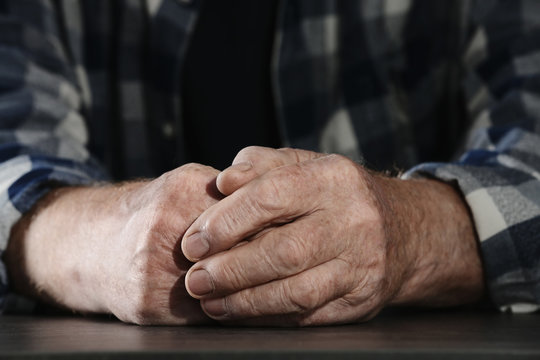 Poor elderly man sitting at table, focus on hands