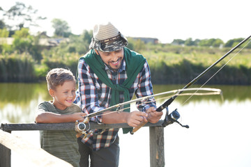Father and son fishing together on sunny day