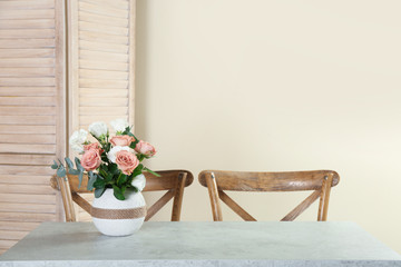 Vase with beautiful flowers as element of interior design on table in room. Space for text