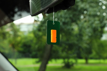 Air freshener hanging in car against windshield