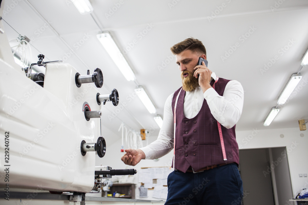 Wall mural Young bearded tailor working on new cloting design